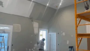 Interior painting project with worker rolling paint on high walls.