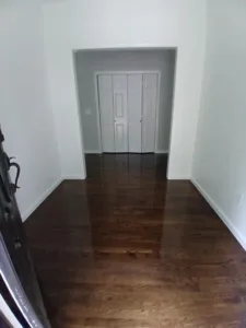 Refinished hardwood floor in hallway with doors in background.