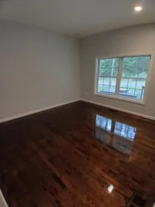 Refinished wood floor in a room, showing a glossy and smooth finish.