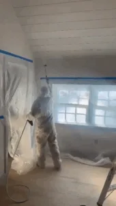 Professional spraying paint on ceiling during hardwood floor refinishing.