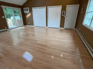Hardwood floor refinishing showing a smooth glossy finish in a bright room.