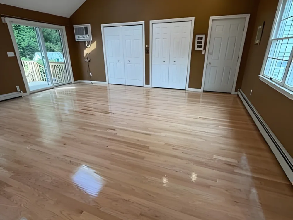 Hardwood floor refinishing showing a smooth glossy finish in a bright room.