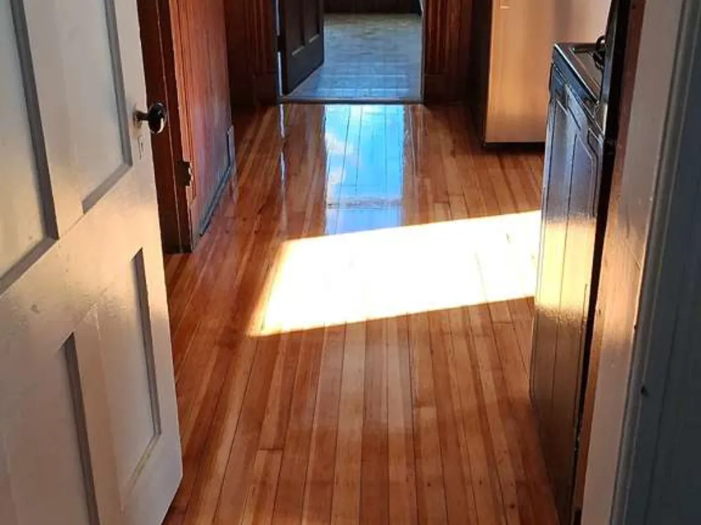 Kitchen hardwood floor refinishing showing worn wood surface before restoration