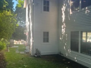 Exterior house painting showing freshly painted white siding on the side elevation of a two-story home.