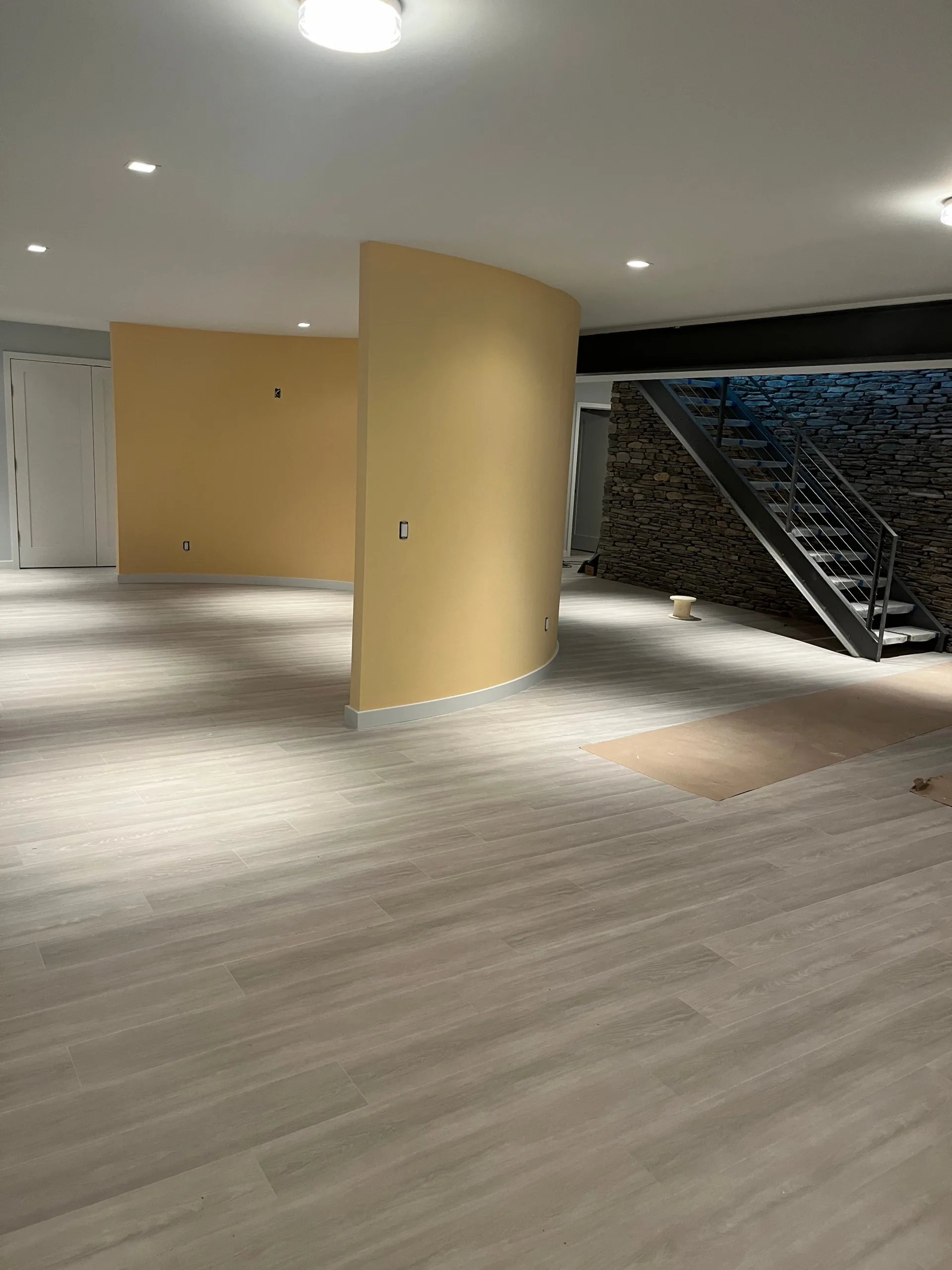 Modern interior renovation highlighting a curved architectural accent wall, new flooring, and staircase detailing.