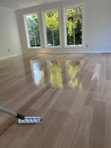 High-gloss results of hardwood floor refinishing Westport in a bright room with large windows.