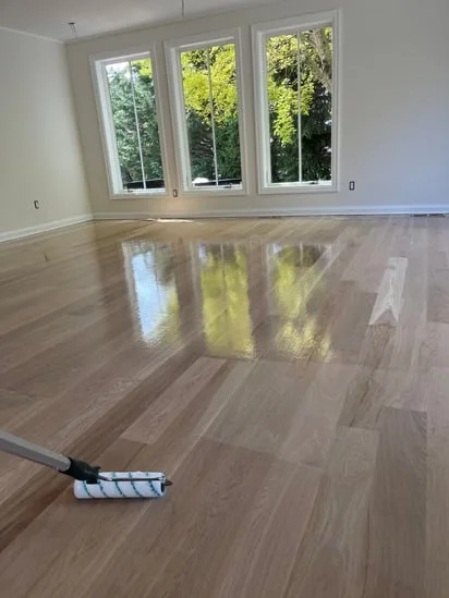 High-gloss results of hardwood floor refinishing Westport in a bright room with large windows.
