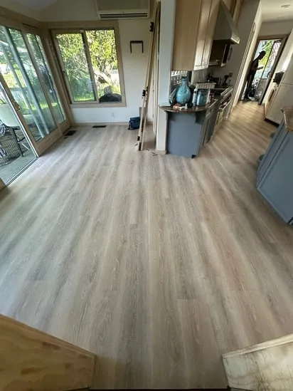 Perspective shot showing light oak vinyl flooring seamlessly connecting the kitchen island and dining area.